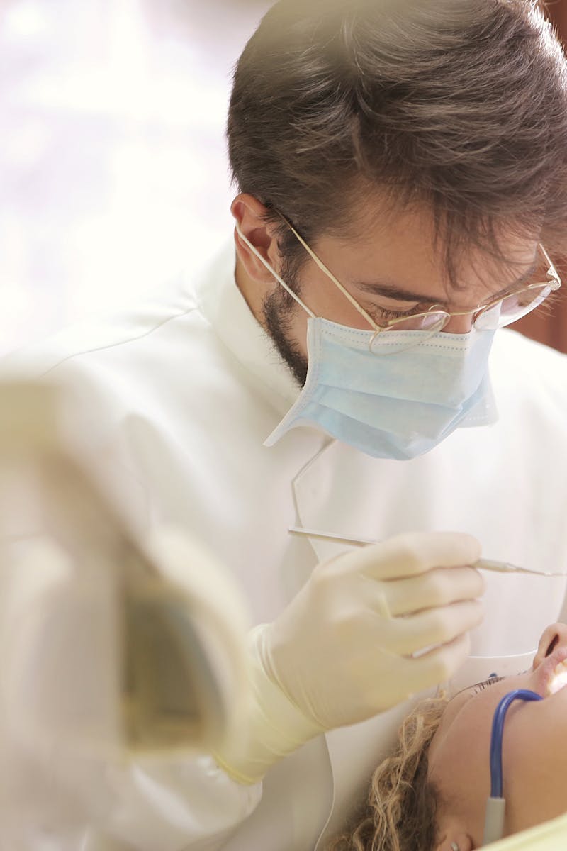 Dentist in face mask conducting a dental examination with tools in clinic setting.