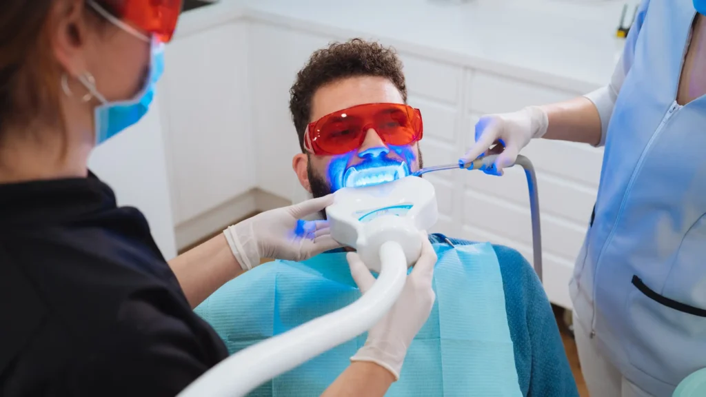 Dentist using laser dentistry treatment during dental check-up.